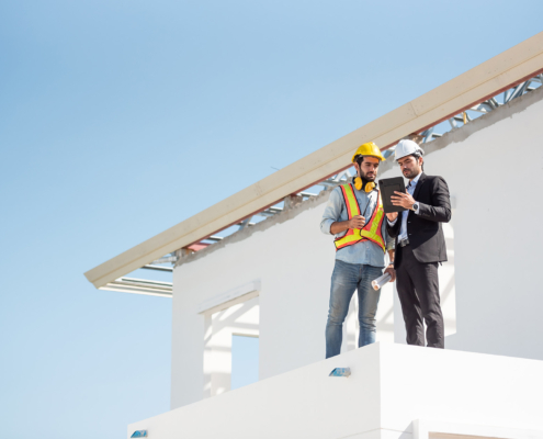 Construction engineer and architect team working together with blueprints discuss on the rooftop outdoor at construction site